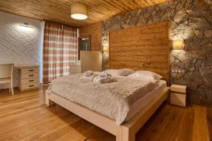 1 dormitorio con 1 cama grande y pared de piedra en Chalet SNOW en Demanovska Dolina