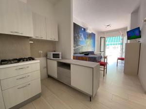 a kitchen with white cabinets and a counter with a microwave at RESIDENCE EL PALMAR FRONTE MARE, FRONTE SPIAGGIA (5 metri), FRONTE PISCINA (4 metri) in Lido di Jesolo