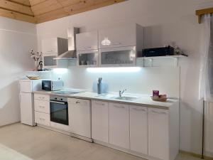 a kitchen with white cabinets and a sink at Apartment Feher Lendava in Lendava +35 photos