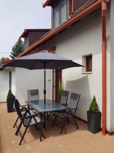 Apartment in Balatonakali 36227 في بالاتوناكالي: طاولة وكراسي مع مظلة على الفناء