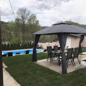 a table and chairs under an umbrella next to a pool at Drinska Idila apartmani in Vrhpolje