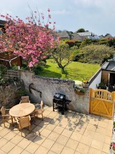 a patio with a table and chairs and a grill at Shepherds House in Swanage +14 photos