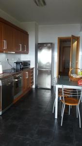 a kitchen with a table and a stainless steel refrigerator at 106 Green North in Ribeira Grande