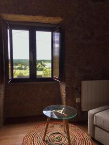 sala de estar con mesa de cristal y ventana en Casas do Torreão 3 casas de alojamento local, en Alfaiates