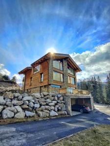 a house on a stone wall with the sun shining on it at Chalet SNOW in Demanovska Dolina