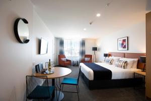 a hotel room with a bed and a table and chairs at Quest Tauranga Central in Tauranga