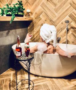 a woman sitting in a bath tub holding a glass of wine at Apartament Góry i Potok in Porąbka