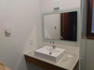 Un baño blanco con lavabo y espejo. en Casa aconchegante em Guaeca - 8 pessoas, en São Sebastião 32 fotos más