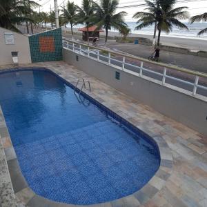 a large blue swimming pool next to a beach at Ótimo apartamento condomínio frente a praia in Mongaguá