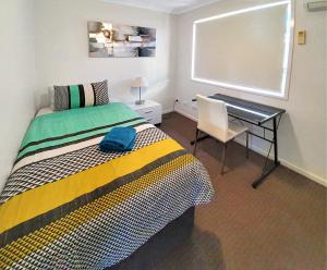a bedroom with a bed and a desk and a window at Lillypilly Resort Apartments in Rockhampton