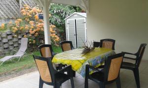 a table and chairs on a patio with a garden at Villa Les Flambloyants in Baréto