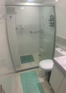 a bathroom with a shower with a toilet and a green rug at Lindo Ap 1102 Vista do Mar c Garagem in Recife