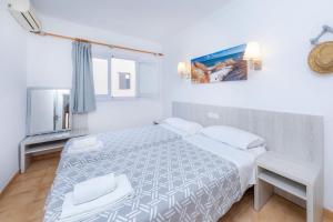 a white bedroom with a bed and a tv at Rosamar Holidays Apartments in Cala Ratjada