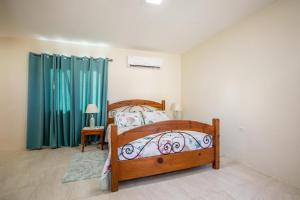 a bedroom with a wooden bed and blue curtains at Serene by the Sea in Savaneta