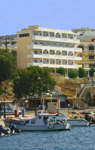 dos barcos atracados en el agua frente a un gran edificio en Sunrise Hotel, en Karpathos