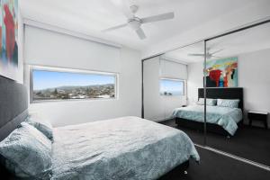 a bedroom with a bed and a large window at Luxury Apartment Caves Beach 4 Bed in Caves Beach