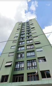 聖保羅的住宿－Apartamento aconchegante com estacionamento na 25 de março，一座高大的绿色建筑,有许多窗户