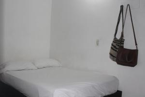 a white bedroom with a bed and a purse on the wall at Hospedaje Primavera in Medellín