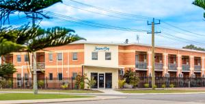 a large orange and white building with palm trees in front at Jurien Bay Motel Apartments in Jurien Bay