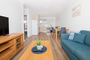 sala de estar con sofá azul y TV en Jurien Bay Motel Apartments, en Jurien Bay