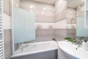 een witte badkamer met een bad en een wastafel bij comfort 66 in Miskolc