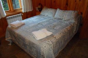 Una cama en una habitación con dos toallas. en Complejo hotelero Illihue - Cabañas & Hostería en Junín de los Andes