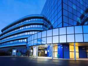 a large glass building with a blue at Novotel Poitiers Site du Futuroscope in Chasseneuil-du-Poitou