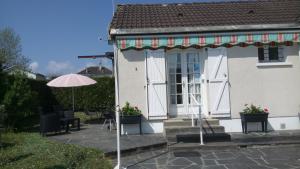 a white house with an umbrella and a patio at Les Gites Lussacois in Lussac-les-Châteaux