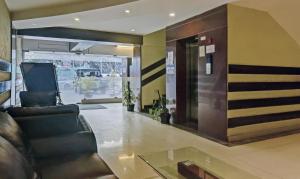 a lobby with a leather couch and a glass table at Treebo Trend Savoury Sea Shell Residency in Bangalore