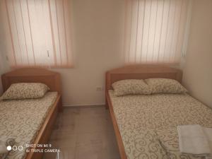 two beds in a small bedroom with two windows at Apartmani ODMOR NA DRINI in Ljubovija