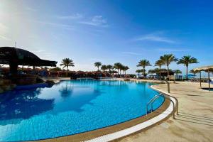 a large swimming pool at a resort with palm trees at Comfy apt by Sentido Marsa Alam in Marsa Alam City