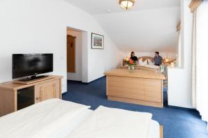 a room with a bed and a tv and two people at Hotel Landgasthof Schöntag in Münsing