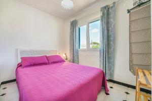 a bedroom with a pink bed and a window at Villas Vanessa & Ruth in Cala'n Porter +16 photos