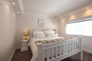 a white bedroom with a white bed and a window at Ellie's Cottages in Stanley