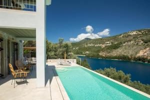 a house with a swimming pool next to a body of water at Villa Anthelia-Idyllic view and private access to the sea in Sivota