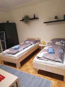 dwa łóżka w pokoju z dwoma stołami w obiekcie Orsi Szálláshelyek Kecskemét 2 w mieście Kecskemét