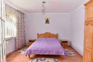 1 dormitorio con cama morada y ventana en Casa Maria en Mănăstirea Humorului