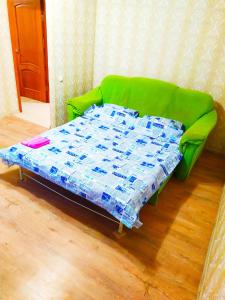 a green couch with a bed in a room at Новострой Прокофьева in Sumy