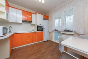 eine Küche mit orangefarbenen Schränken und einem weißen Kühlschrank in der Unterkunft Елизаветы Чавдар 34 in Kiew