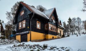 a black and yellow house in the snow at Drevenica Michael in Liptovský Trnovec