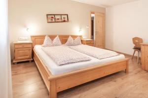 Un dormitorio con una gran cama de madera con sábanas blancas. en Apartments Silva Alpenblick, en San Giovanni in Val Aurina