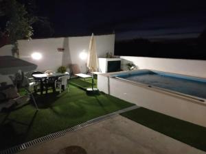 a patio with a table and a swimming pool at night at Casa da Avó Rita in São Pedro do Corval