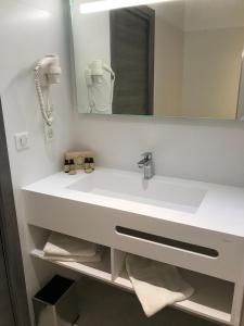 a bathroom with a white sink and a mirror at Hôtel L'Isula Marina in LʼÎle-Rousse