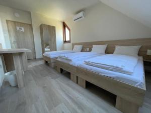 um quarto com 2 camas e lençóis brancos em Szőlőfürt Fogadó em Kecskemét