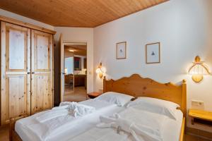 sypialnia z białym łóżkiem z drewnianym zagłówkiem w obiekcie Ferienapartment Kanzelhöhe an der Skipiste w mieście Kanzelhöhe