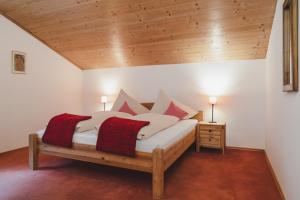 - une chambre avec un lit doté d'oreillers rouges et blancs dans l'établissement Landhaus Elke, à Reith bei Seefeld