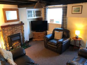 a living room with a couch and a fireplace at Mena Cottage, Cosy Country and Quaint. in Hunmanby