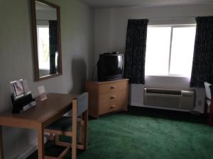 a living room with a desk and a television and a window at Economy Inn - Lafayette in Lafayette