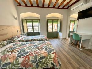 a bedroom with two beds and a desk at La Despensa de la Corredera Hostal in Córdoba