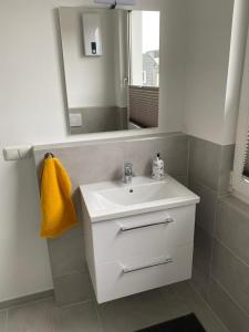 y baño con lavabo blanco y espejo. en FEDDERSEN LIVING Moderne Ferienwohnungen - Gemütlich - Netflix - Voll ausgestattet - Waschmaschine - zentral gelegen, en Brunsbüttel